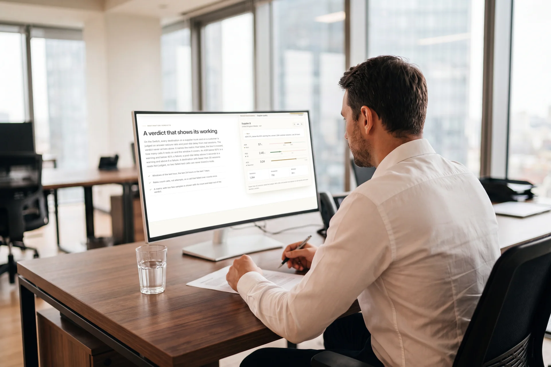 An analyst taking notes at his desk, the PacketExchange destination verdict for a supplier route open on his monitor