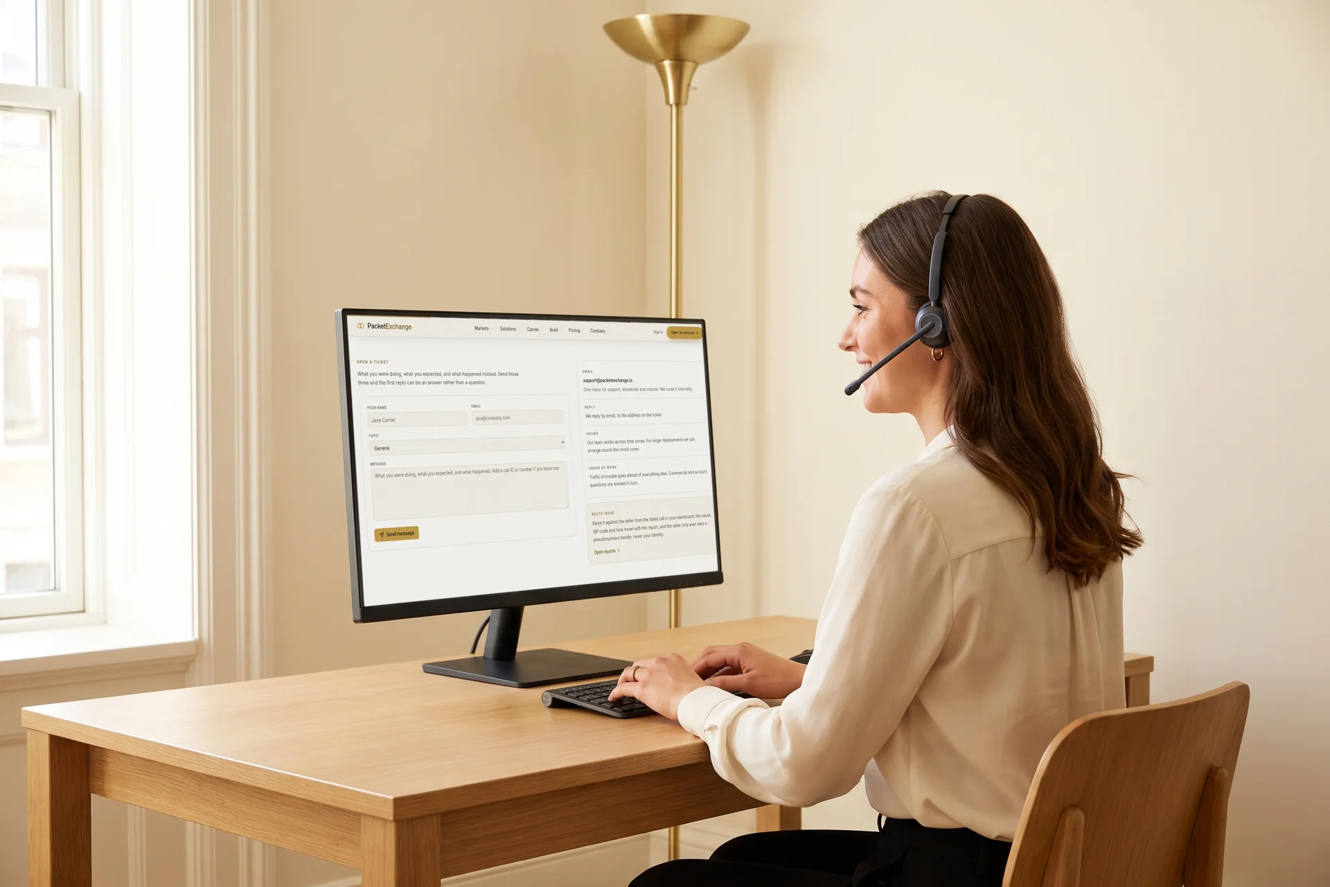 A support specialist in a headset typing a reply at her desk, the PacketExchange support page open on her monitor